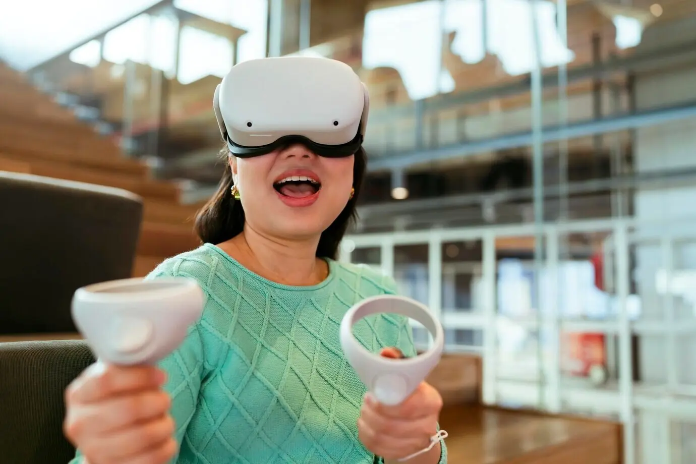 Aufregende asiatische Gamerin beim futuristischen 3D-Gaming in der virtuellen Realität und im erweiterten Metaverse; schöne junge Frau mit VR-Brille, die mit Spaß und Freude spielt.